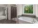 Modern bathroom showcases a soaking tub, glass-enclosed shower, and a view of natural greenery at 265 Umstead St, Sanford, NC 27330