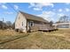 Rear exterior view of the home, showcasing the siding and small deck, surrounded by a grassy lawn at 3307 Altamahaw Church St, Elon, NC 27244