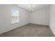 Clean and vacant bedroom featuring neutral walls, plush carpet, a window for natural light, and a modern chandelier at 5332 Seaspray Ln, Raleigh, NC 27610