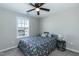 Cozy bedroom with floral bedding, ceiling fan, a window, and a dark-colored nightstand at 5917 Kayton St, Raleigh, NC 27616