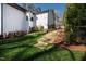 Landscaped backyard with grass and stone steps leading to a modern two-story home at 6816 Rainwater Rd, Raleigh, NC 27615