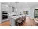 A modern, gray kitchen features a large island with seating and pendant lighting. Stainless steel appliances at 6816 Rainwater Rd, Raleigh, NC 27615