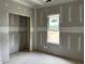 An unfinished bedroom with drywall, a window letting in natural light, and an empty closet space at 896 Olive Branch Dr, Smithfield, NC 27577
