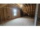 Unfinished attic with exposed beams, plywood flooring, window, and dark insulation at 105 Leisure Ln, Louisburg, NC 27549