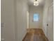 Bright hallway with hardwood floors, white walls, a modern light fixture, and a white back door at 105 Leisure Ln, Louisburg, NC 27549