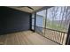 Covered screened porch with stained wood flooring, black railing, and view of wooded backyard at 105 Leisure Ln, Louisburg, NC 27549