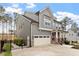 Stylish gray home showcasing a two-car garage, and welcoming covered porch with stone accents at 105 Mystic Quartz Ln, Holly Springs, NC 27540