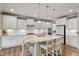 Bright kitchen with white cabinets, a large island with seating and stainless-steel appliances with hardwood floors at 105 Mystic Quartz Ln, Holly Springs, NC 27540