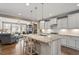 Open-concept kitchen with white cabinetry, granite island with seating, stainless appliances and view to living room at 105 Mystic Quartz Ln, Holly Springs, NC 27540