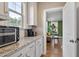 Kitchenette features white cabinets, granite countertops and stainless-steel appliances with view to living room at 105 Mystic Quartz Ln, Holly Springs, NC 27540