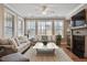 Bright living room features a fireplace, hardwood floors, large windows, ceiling fan and neutral-toned furniture at 105 Mystic Quartz Ln, Holly Springs, NC 27540