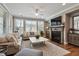 Cozy living room features a fireplace, hardwood floors, large windows, ceiling fan and neutral-toned furniture at 105 Mystic Quartz Ln, Holly Springs, NC 27540