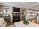 Open living room with fireplace, flat screen television and white cabinets, open to kitchen area at 105 Mystic Quartz Ln, Holly Springs, NC 27540