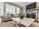 Cozy living room features a fireplace, hardwood floors, large windows, ceiling fan and neutral-toned furniture at 105 Mystic Quartz Ln, Holly Springs, NC 27540