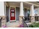 Inviting front porch with decorative columns, red door, and well-maintained landscaping at 105 Mystic Quartz Ln, Holly Springs, NC 27540