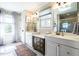 Well-lit bathroom with double sinks, modern vanity, and large mirrors reflecting natural light from the window at 106 Nashua Cv, Louisburg, NC 27549