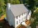 An eye-level view of a white brick two-story home with a gray roof surrounded by trees at 1222 Dixie Trl, Raleigh, NC 27607