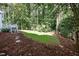 Secluded backyard with a well-manicured lawn, mature trees, and a stepping stone pathway leading to a deck, perfect for outdoor enjoyment at 1222 Dixie Trl, Raleigh, NC 27607