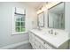 Bright bathroom featuring double sinks, marble counters, a window with shades and tiled floors at 1222 Dixie Trl, Raleigh, NC 27607