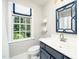Well-lit bathroom featuring a white vanity with blue cabinet, a modern mirror, and a window at 1222 Dixie Trl, Raleigh, NC 27607