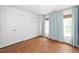 Bright bedroom featuring hardwood floors, double door closet, and window with light blue curtains at 1222 Dixie Trl, Raleigh, NC 27607