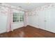 Charming bedroom featuring floral wallpaper, hardwood floors, and natural light from a window with pink curtains at 1222 Dixie Trl, Raleigh, NC 27607