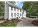 Charming two-story brick home featuring a manicured lawn, a paved driveway, mature trees, and a welcoming facade at 1222 Dixie Trl, Raleigh, NC 27607