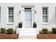 Inviting front entrance with a light blue door, decorative wreath, elegant sconces, and manicured landscaping at 1222 Dixie Trl, Raleigh, NC 27607