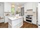 Beautiful, all-white kitchen featuring an island, modern appliances, and hardwood floors at 1222 Dixie Trl, Raleigh, NC 27607