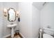 Charming powder room with pedestal sink, decorative mirror, and unique wallpaper at 1222 Dixie Trl, Raleigh, NC 27607
