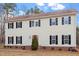 View of the two-story home with black shutters, a red front door, brick foundation, and fresh landscaping at 125 Vance Wrenn Rd, Roxboro, NC 27573