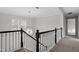 Hallway featuring a modern chandelier, dark wood railing, neutral carpet, and natural light at 125 Vance Wrenn Rd, Roxboro, NC 27573