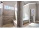 Modern bathroom with tiled shower and bench, tub, and a window overlooking the outdoors at 1412 Wynncrest Ct, Raleigh, NC 27603