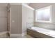 Bright bathroom featuring a shower and a soaking tub with tile surround and a frosted window at 1412 Wynncrest Ct, Raleigh, NC 27603