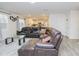 Spacious living room with a large brown leather sectional, glass table, and view of the bright, white kitchen at 2121 Wildwind Dr, Graham, NC 27253
