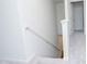 Carpeted stairway features a metal handrail and white walls, leading to a bright hallway with a closed white door at 2121 Wildwind Dr, Graham, NC 27253