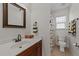 A clean and vibrant bathroom featuring wood vanity, bright window, and dinosaur-themed shower curtain at 22 Old York Cir, Clayton, NC 27527