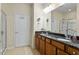 Bathroom featuring double sinks, granite countertops, wood cabinets, a large mirror, and a glass shower at 241 Lifeson Way, Cary, NC 27519