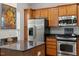 Well-lit kitchen featuring stainless steel appliances, wooden cabinets, and dark granite countertops at 241 Lifeson Way, Cary, NC 27519
