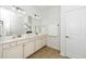 Bright bathroom featuring a double sink vanity with white countertops, a large mirror, and neutral flooring at 2436 Fiddich Ln, Fuquay Varina, NC 27526