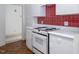 Well-lit kitchen featuring white cabinets, red backsplash and electric stove at 595 Weathersfield # A, Pittsboro, NC 27312