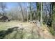 Spacious backyard with a fire pit, fenced perimeter, wood pile, and mature trees at 704 Vance St, Mebane, NC 27302
