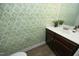 A bathroom with green leaf-patterned wallpaper, a pedestal sink, and white toilet at 704 Vance St, Mebane, NC 27302