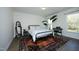 Bright bedroom featuring a queen bed with decorative patterned bedding, an area rug, and a large window for natural light at 704 Vance St, Mebane, NC 27302