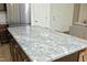 A kitchen island with seating and a gray granite countertop next to stainless steel refrigerator at 704 Vance St, Mebane, NC 27302