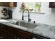 A kitchen sink with black faucet and soap dispenser below a window with various plants on the ledge at 704 Vance St, Mebane, NC 27302
