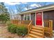 Close up of home showcasing the charming red door and a cozy, covered front porch at 95 Blueberry Rdg, Pittsboro, NC 27312