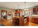 Kitchen featuring wood floors, wooden cabinets and island with bar seating beneath pendant lighting at 95 Blueberry Rdg, Pittsboro, NC 27312