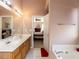 Bathroom featuring double sinks, a soaking tub, and a view into the primary bedroom at 101 Tiverton Woods Dr, Holly Springs, NC 27540