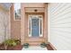 Close up of a blue front door surrounded by brick, potted flowers, and a decorative wreath at 104 Barnes Spring Ct, Cary, NC 27519